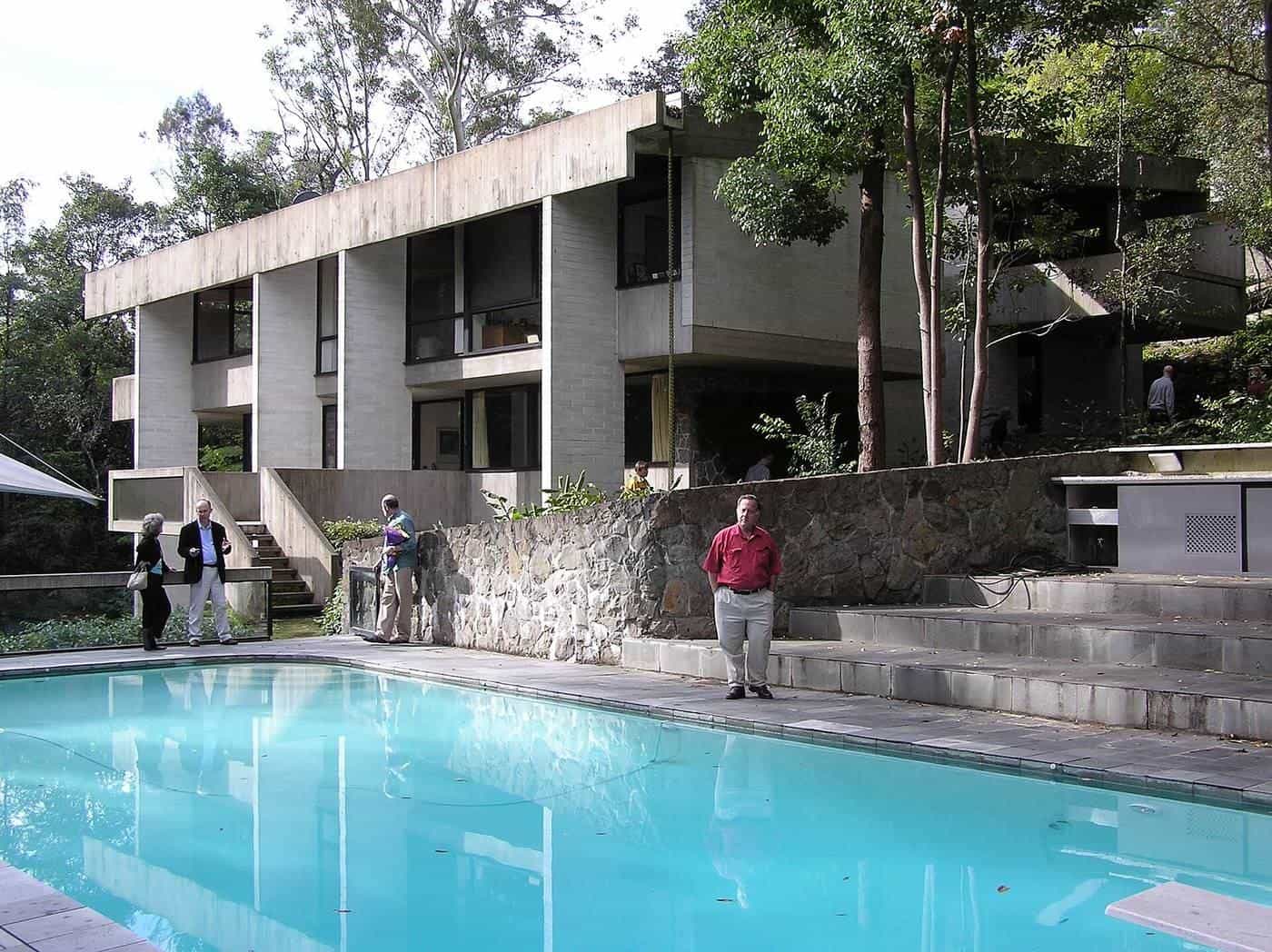 A pool beside a modernist house surrounded by bushland