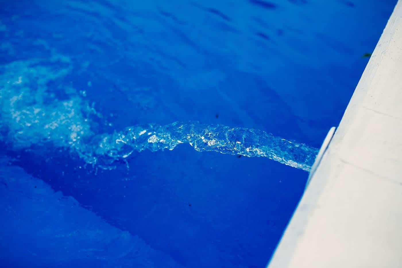Water flowing into a bright blue swimming pool on a sunny day