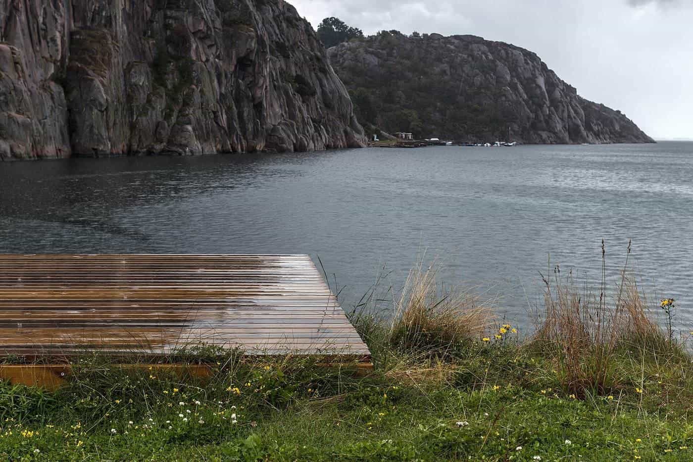 Rain drops on a wet timber deck beside the water