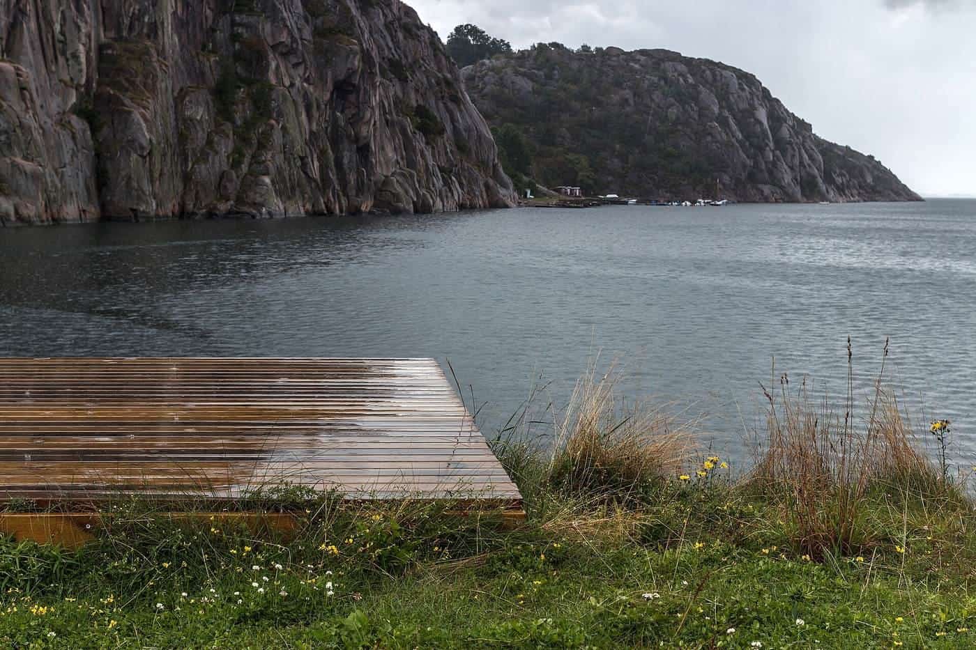 Rain drops on a wet timber deck beside the water